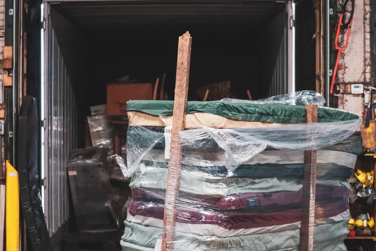 Tall shrink-wrapped pallet of mattresses staged at a warehouse loading dock for shipment